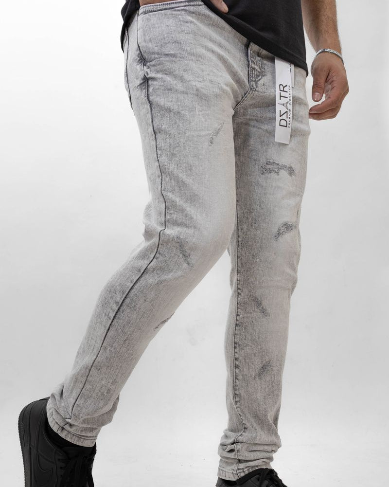 Person wearing light gray distressed jeans with a brand label on a white background