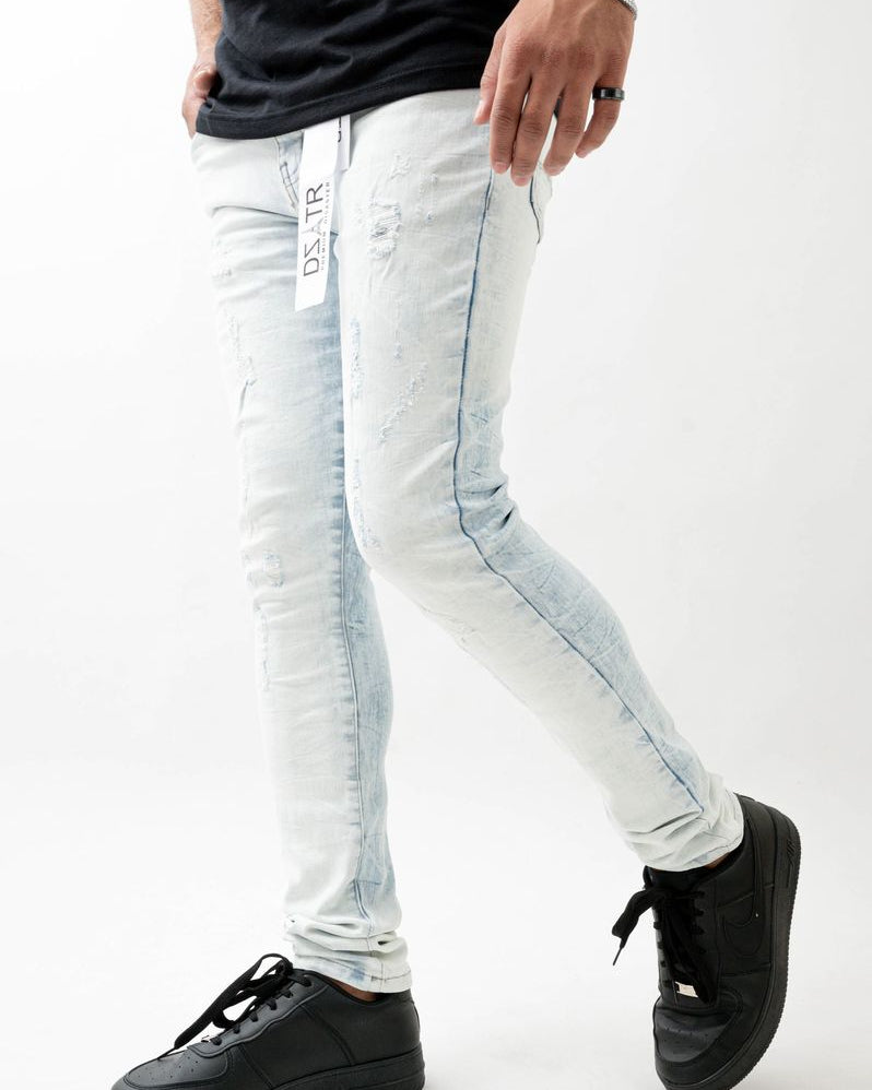 Person wearing light blue jeans with a brand logo and black sneakers on a white background