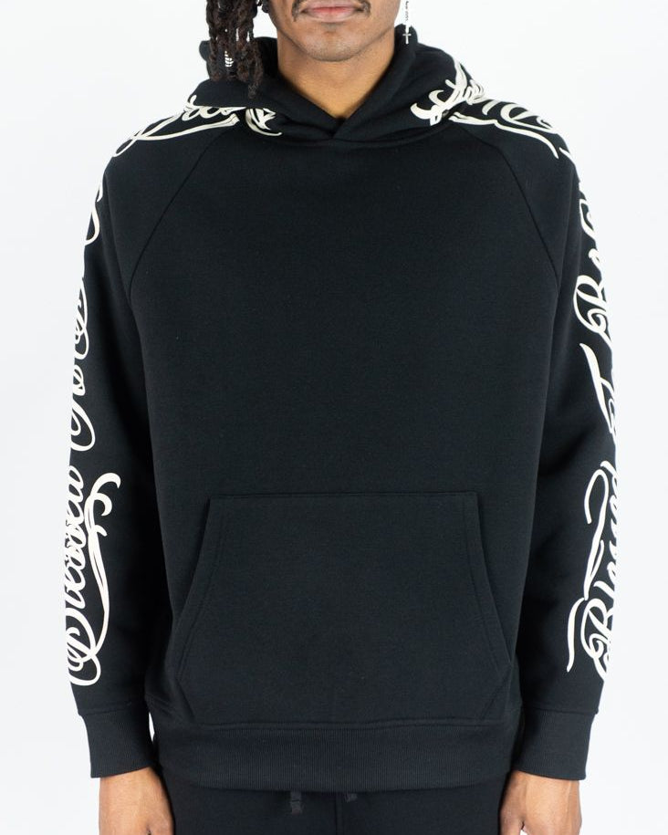 Black hoodie with white designs on sleeves worn by a person against a white background