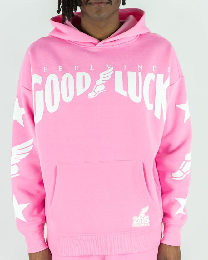 Person wearing a pink hoodie with 'Good Luck' text on a white background