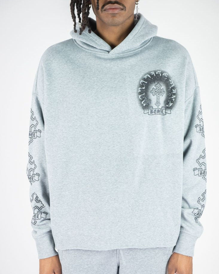 Person wearing a gray hoodie with a logo and matching pants on a white background