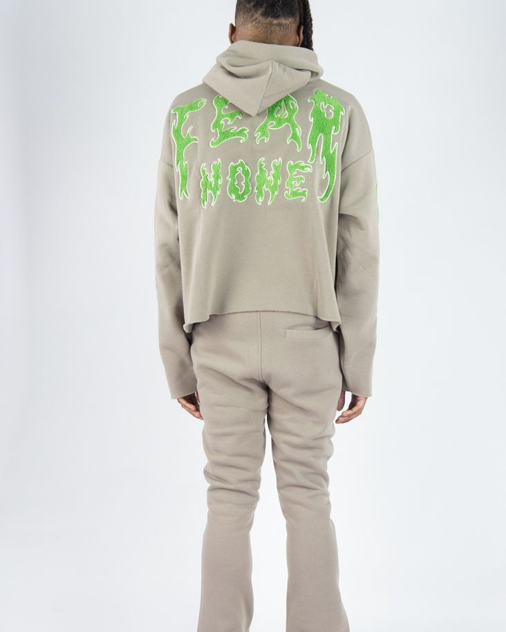 Person wearing a beige tracksuit with green text on the back against a white background