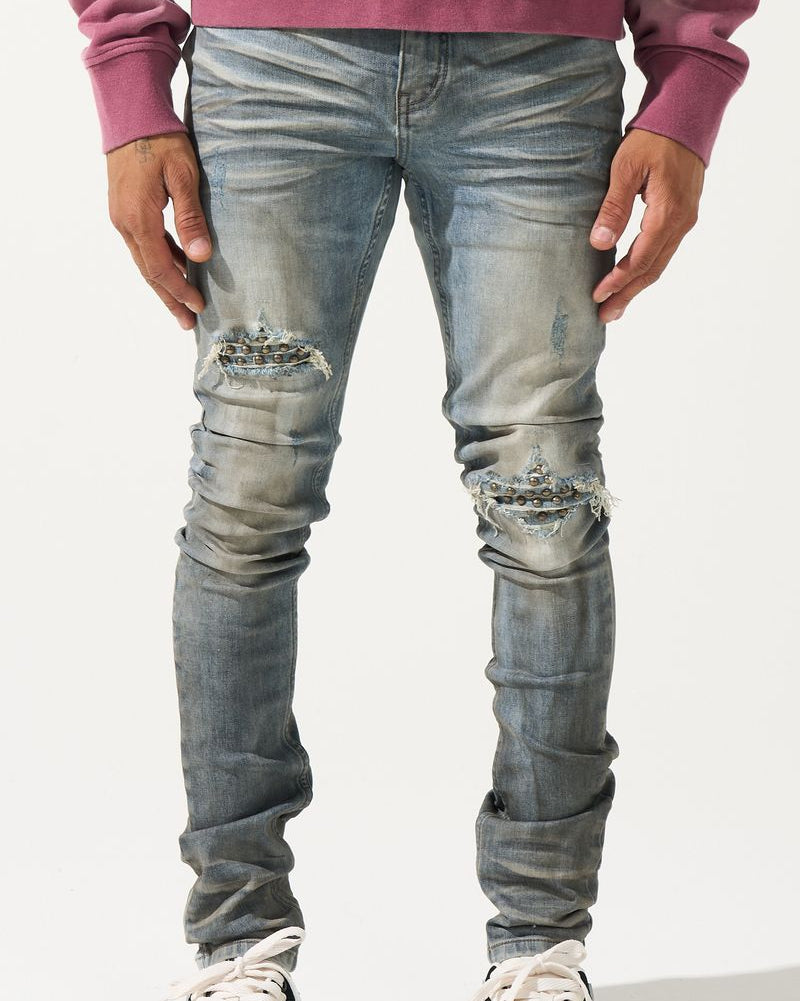 Person wearing distressed blue jeans and black and white sneakers on a white background