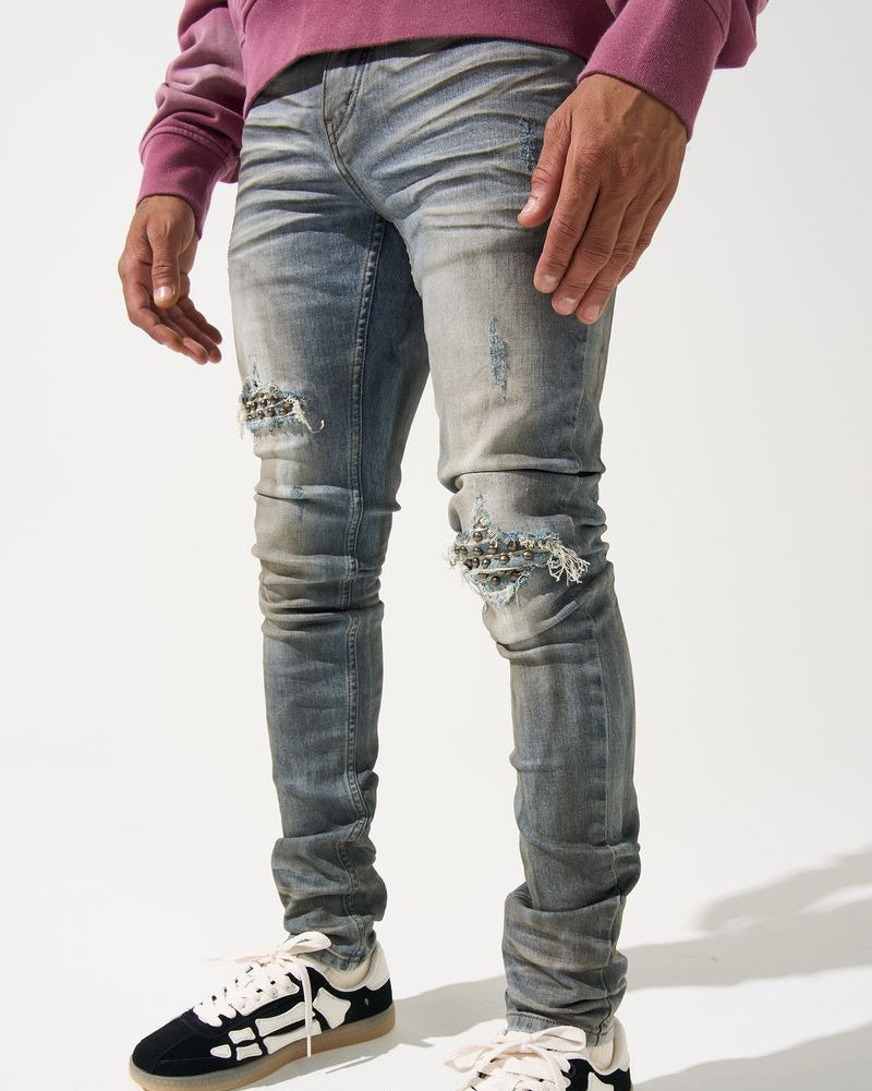 Person wearing distressed gray jeans and black and white sneakers on a white background
