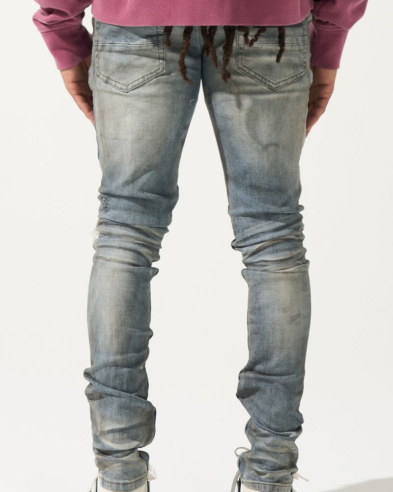 Person wearing light blue jeans and a purple top on a white background