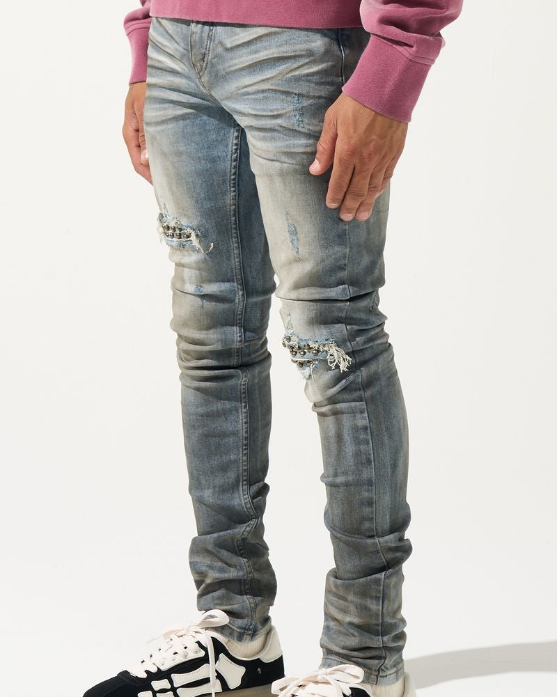 Person wearing distressed gray jeans and black and white sneakers on a white background