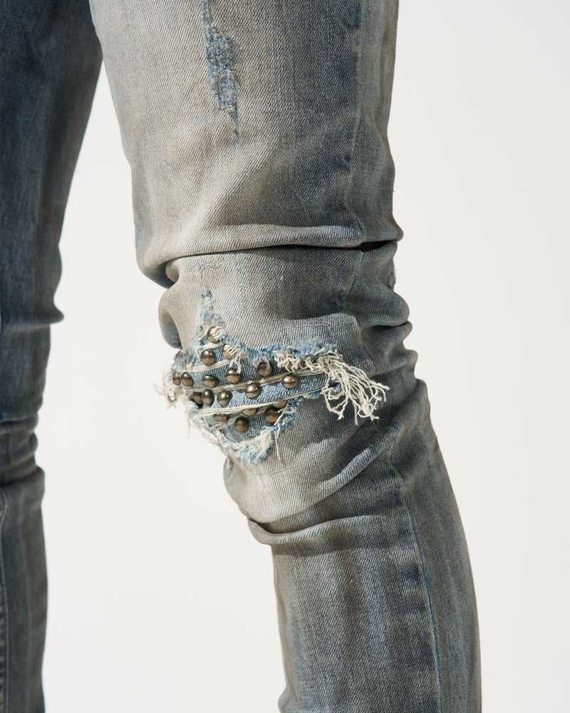 Close-up of distressed jeans with embellishments on a white background