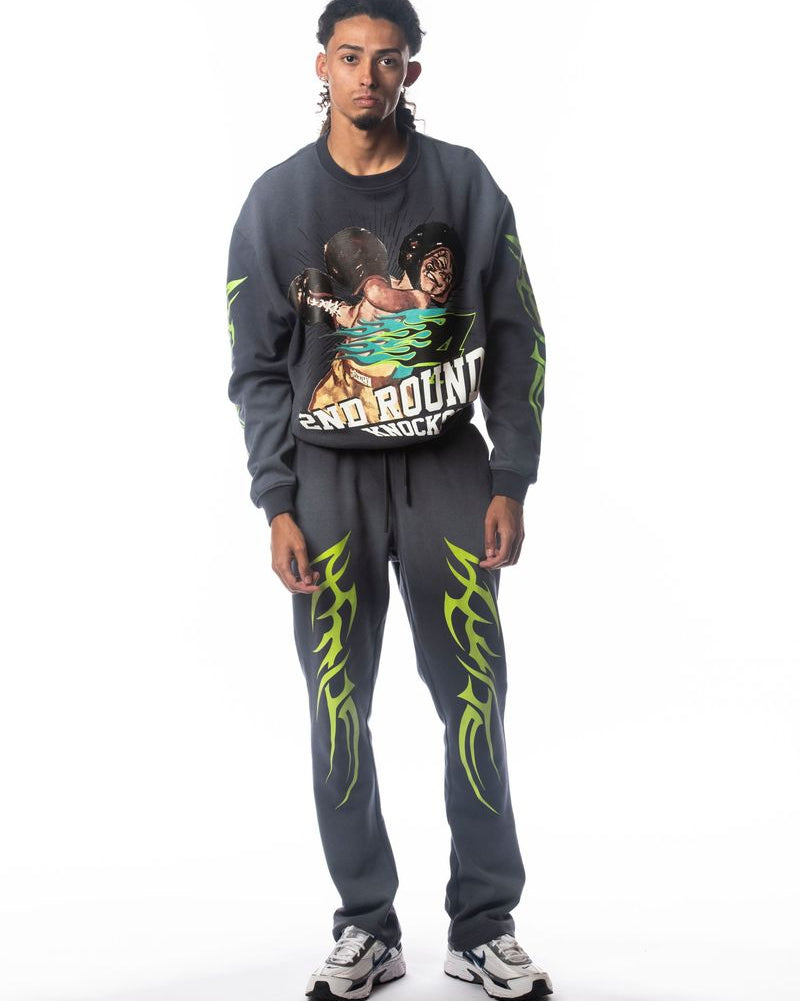 Person wearing a graphic sweatshirt and pants with tribal designs on a white background