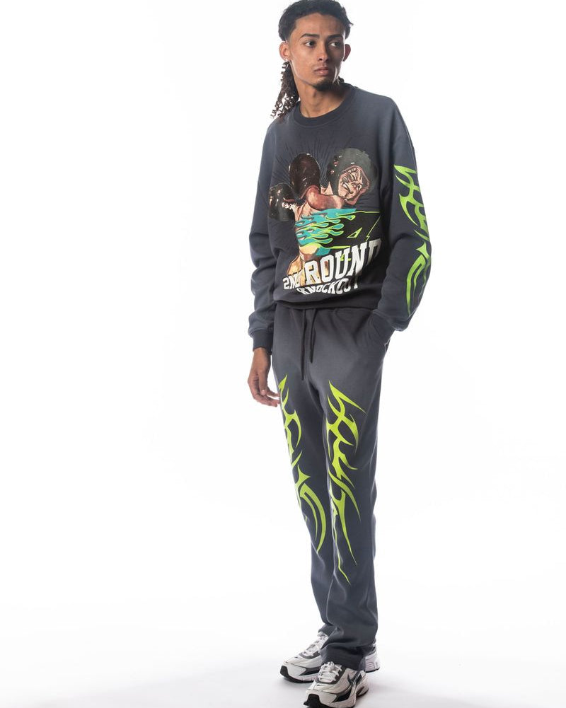 Person wearing a gray sweatshirt and pants with green designs on a white background