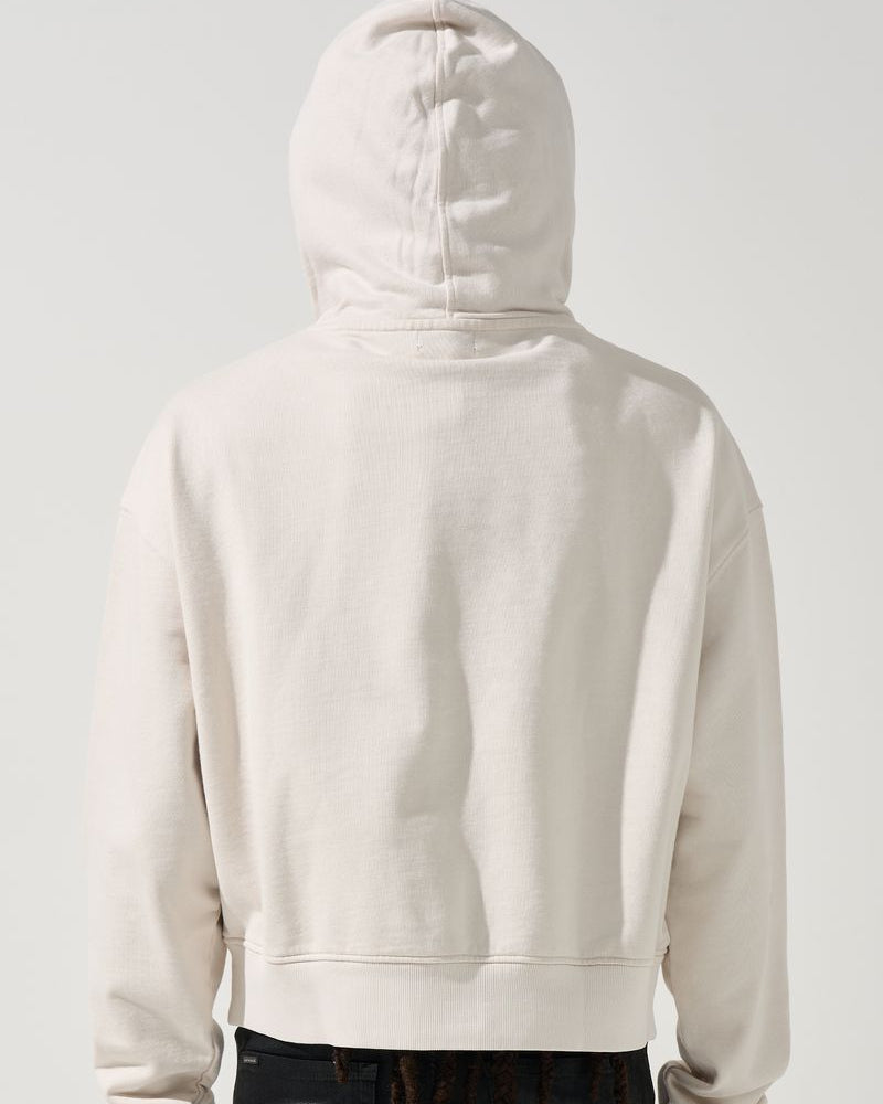 Person wearing a beige hoodie with the back facing the camera on a white background