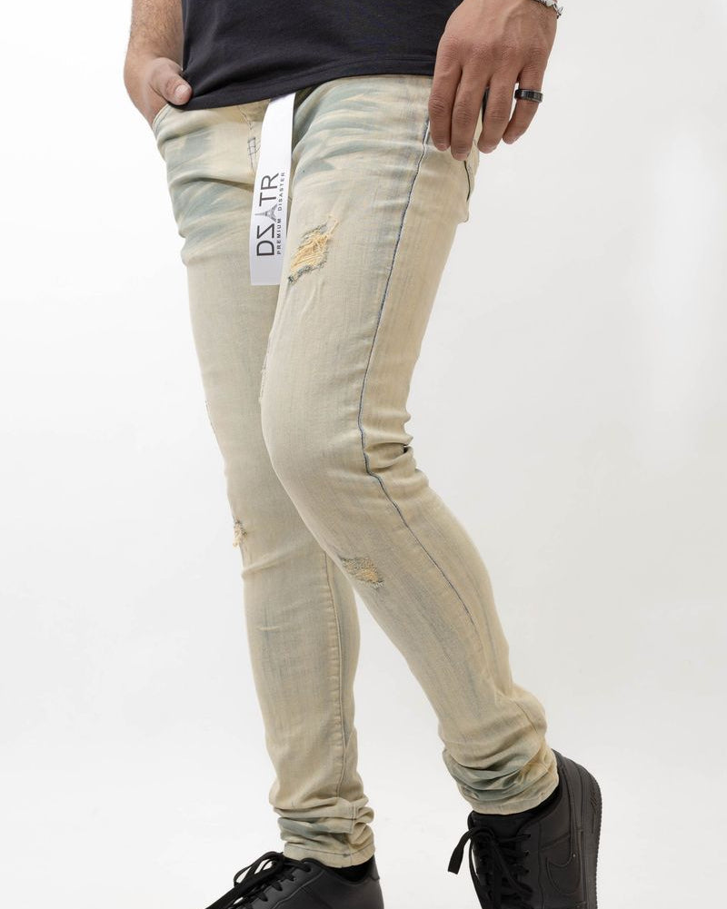 Person wearing beige distressed jeans with a visible brand label on a white background