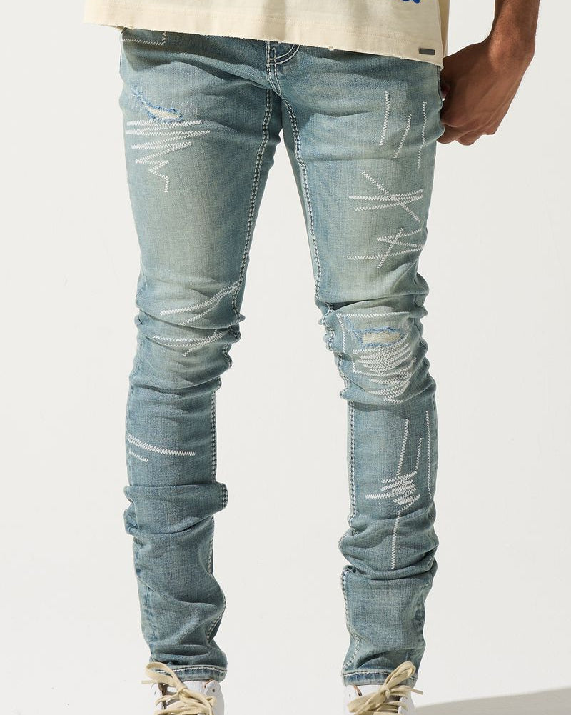 Person wearing light blue distressed jeans and colorful sneakers on a white background