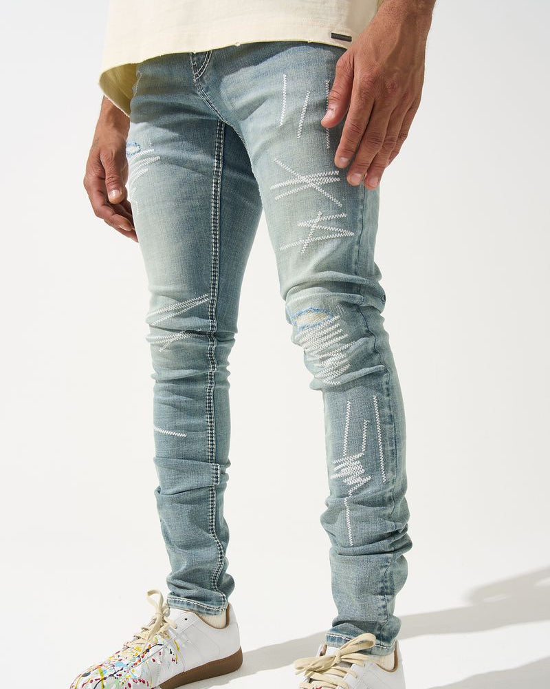 Person wearing light blue distressed jeans and colorful sneakers on a white background