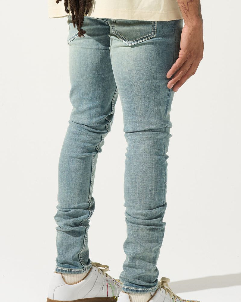 Person wearing light blue jeans and white sneakers on a white background