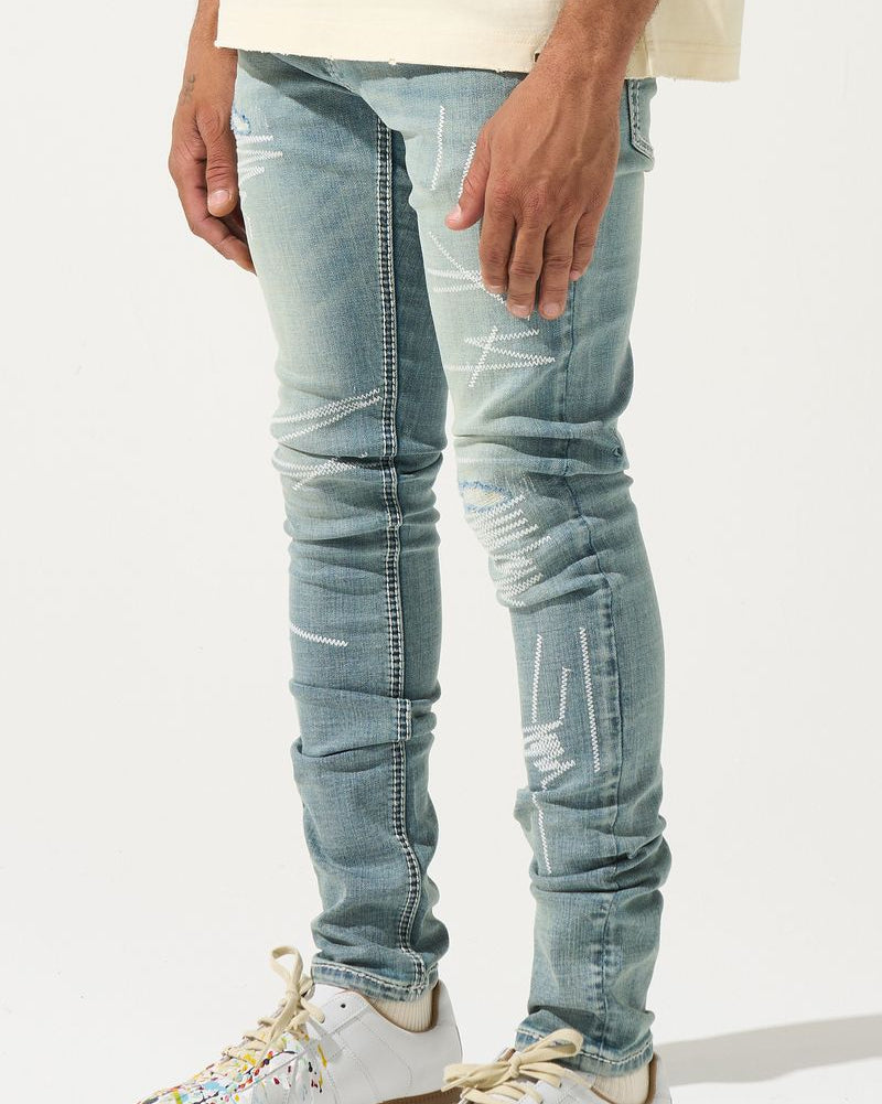Person wearing light blue distressed jeans and white sneakers with brown soles on a white background