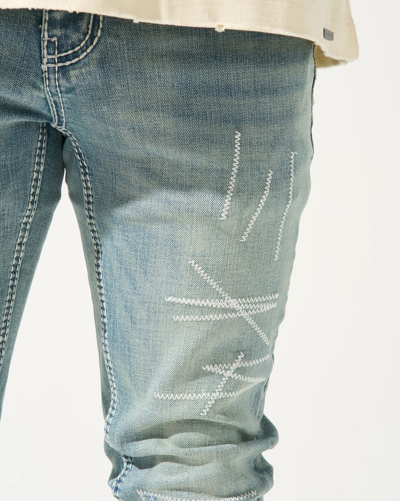 Close-up of blue jeans with white stitching on a white background