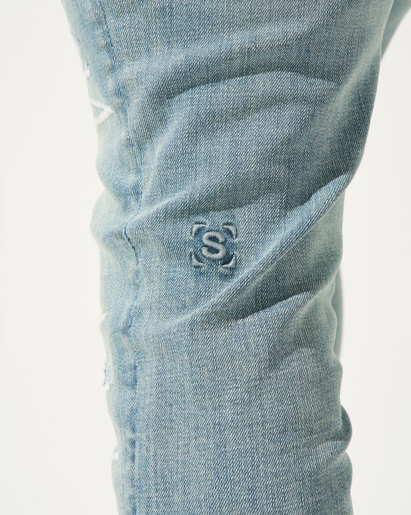 Close-up of light blue denim jeans with a brand logo on the pocket.
