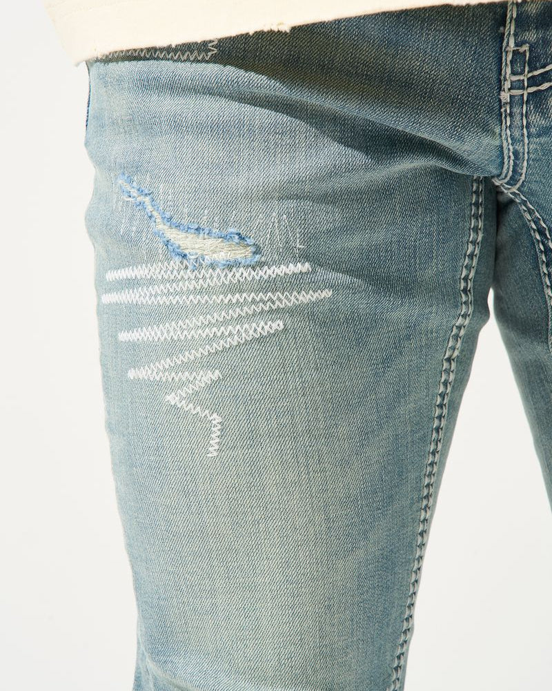 Close-up of distressed blue jeans on a white background