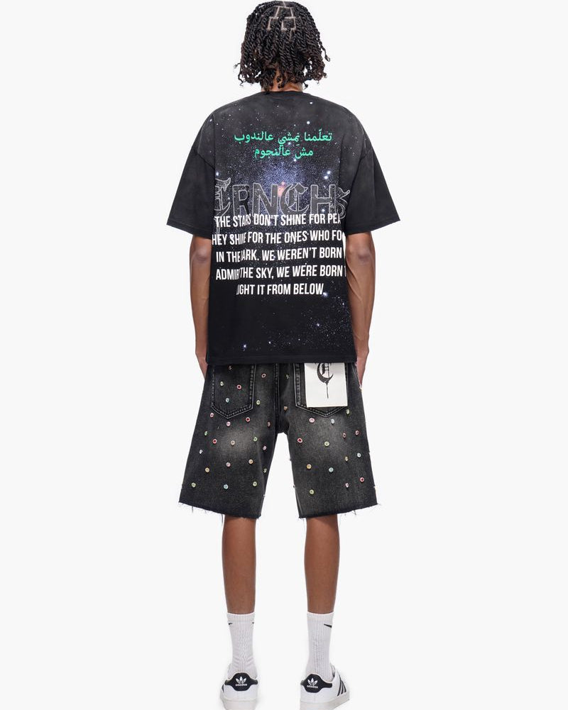 Person wearing a black t-shirt with text and graphic design, standing against a white background