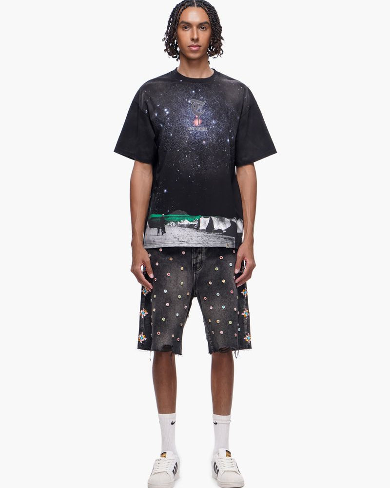 Person wearing a black t-shirt with space-themed design and matching shorts on a white background