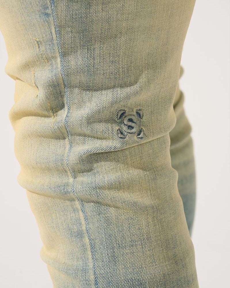 Close-up of a light blue denim pocket with a brand logo on a white background