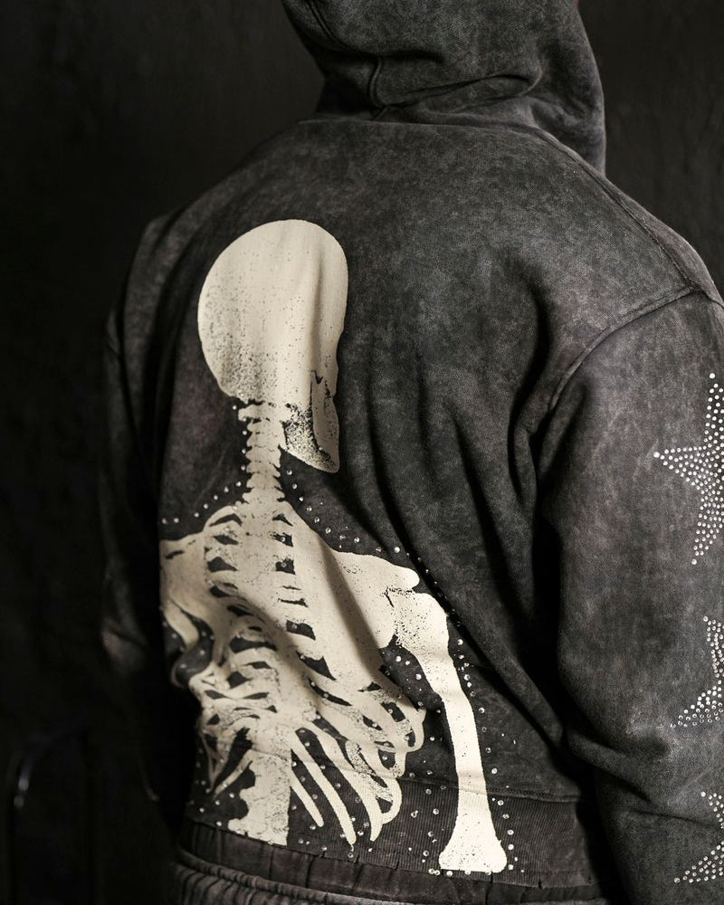 Person wearing a dark hoodie with a skeleton design on the back against a black background