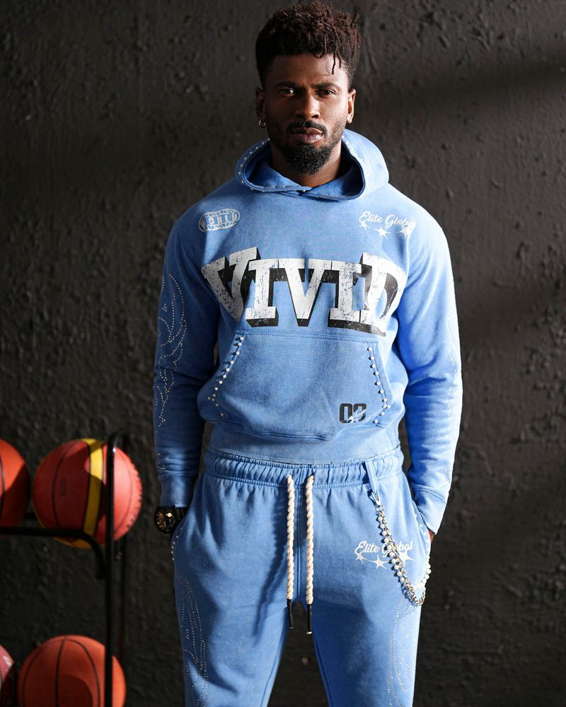 Person wearing a blue 'Vivid' tracksuit with basketballs in the background