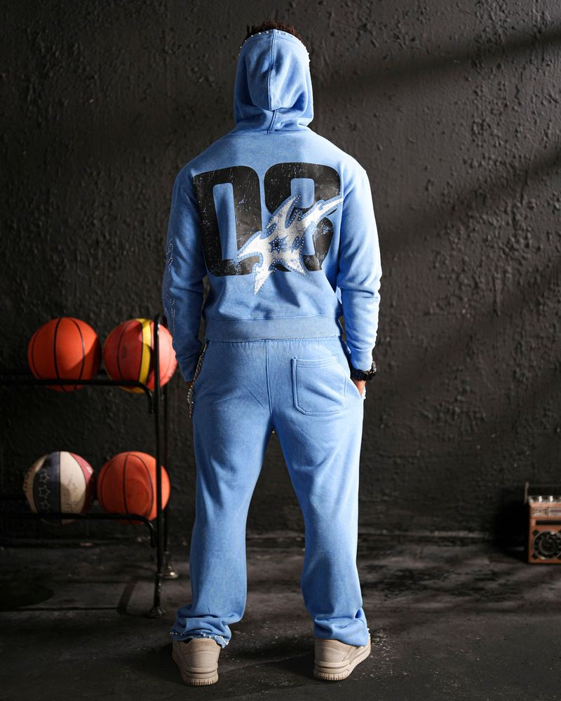 Person wearing a blue hoodie with a logo, standing in a dark room with sports balls on a shelf.