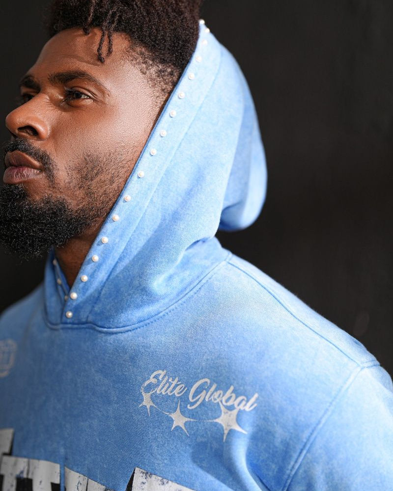 Man wearing a blue hoodie with 'Elite Global' branding against a dark background
