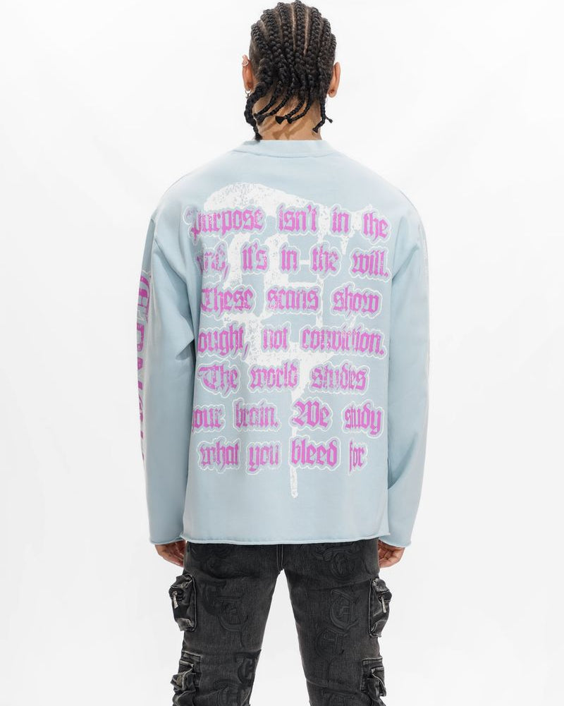 Person wearing a light blue long-sleeve shirt with pink text on the back, standing against a white background.