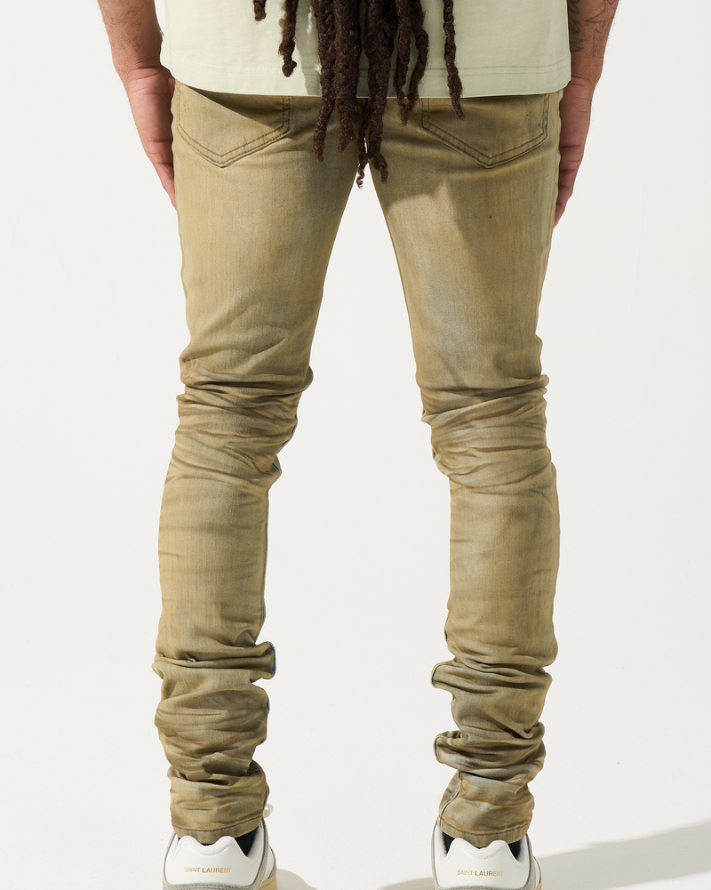 Person wearing beige jeans and white sneakers on a plain background