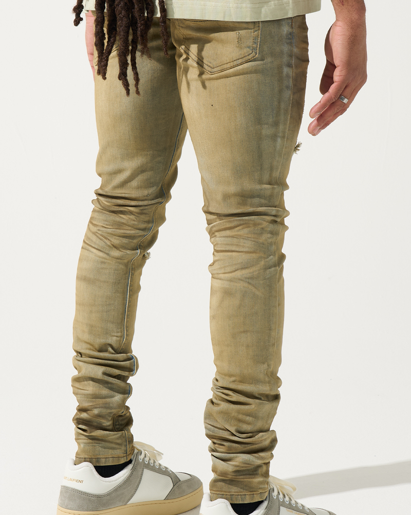 Person wearing beige jeans and white sneakers on a light background