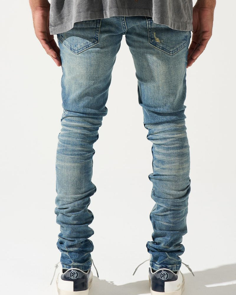 Person wearing blue jeans and white sneakers on a plain background