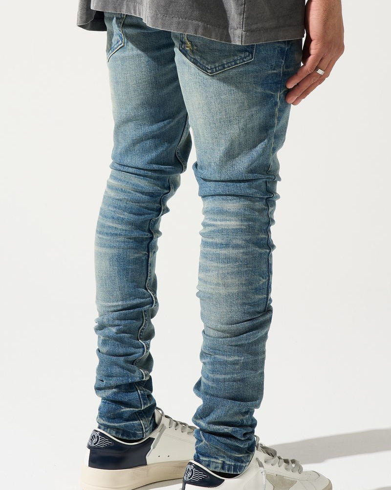 Person wearing blue jeans and white sneakers on a light gray background
