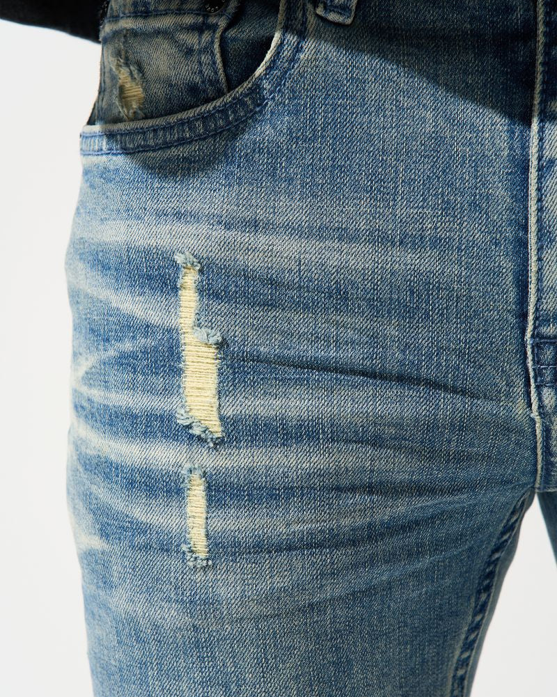 Close-up of distressed blue jeans with a white background