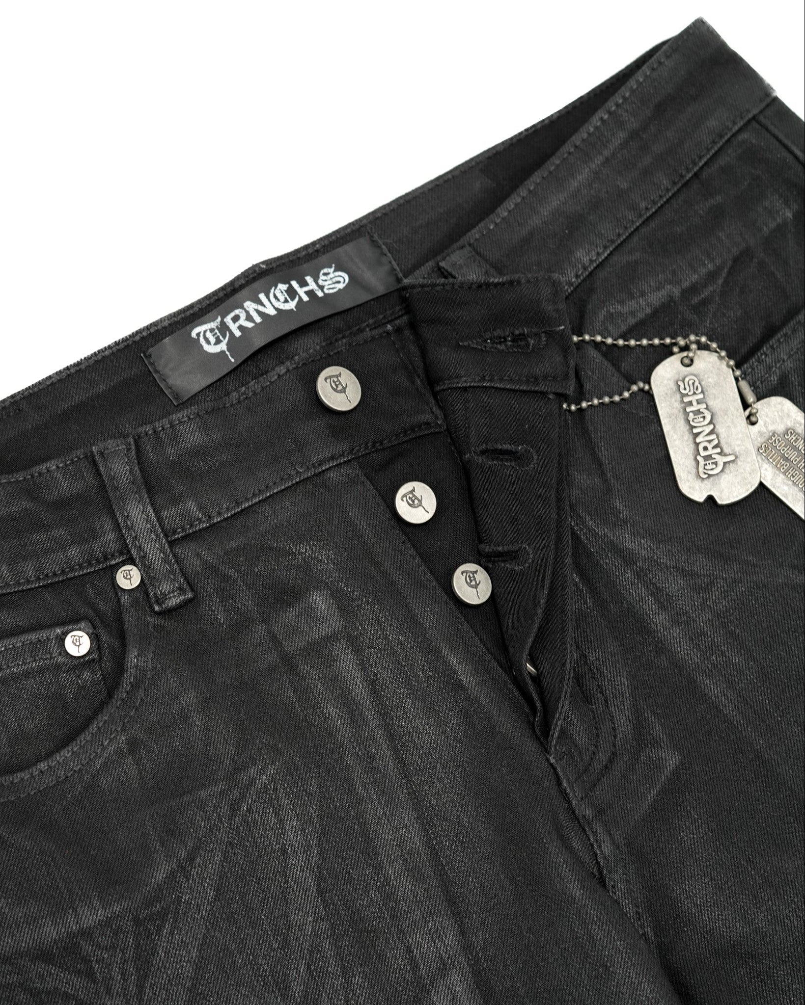 Close-up of black jeans with brand labels on a white background