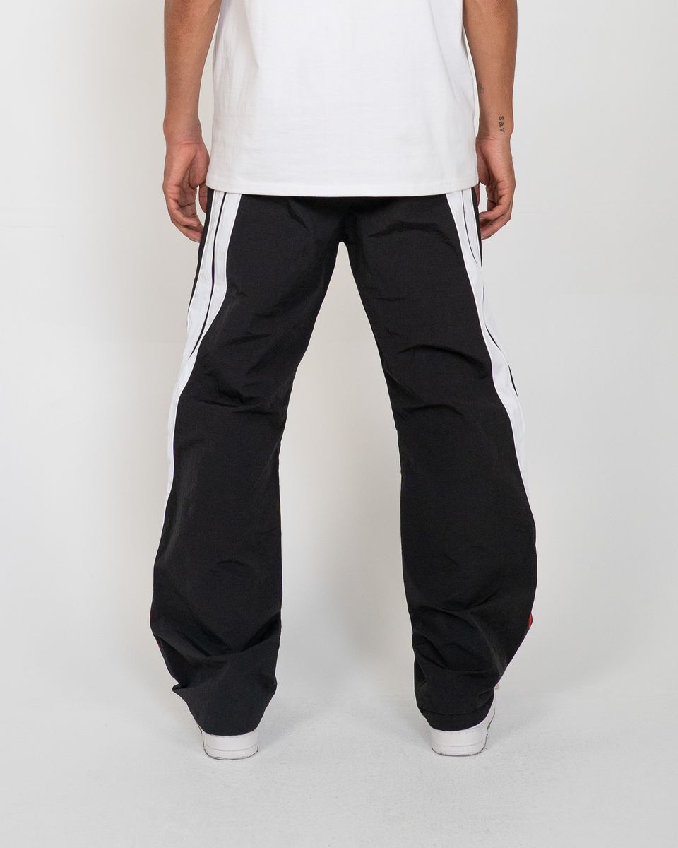 Person wearing black pants with white stripes on a white background
