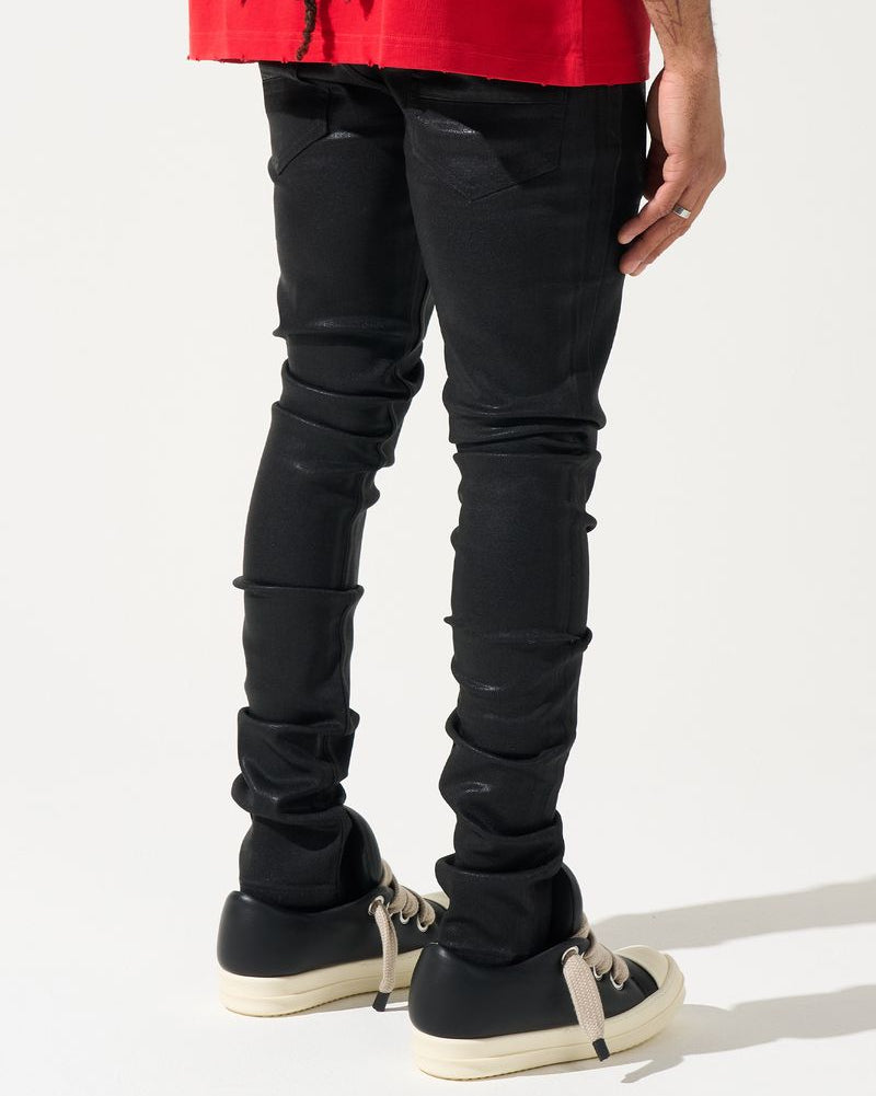 Person wearing black distressed jeans and black sneakers on a white background