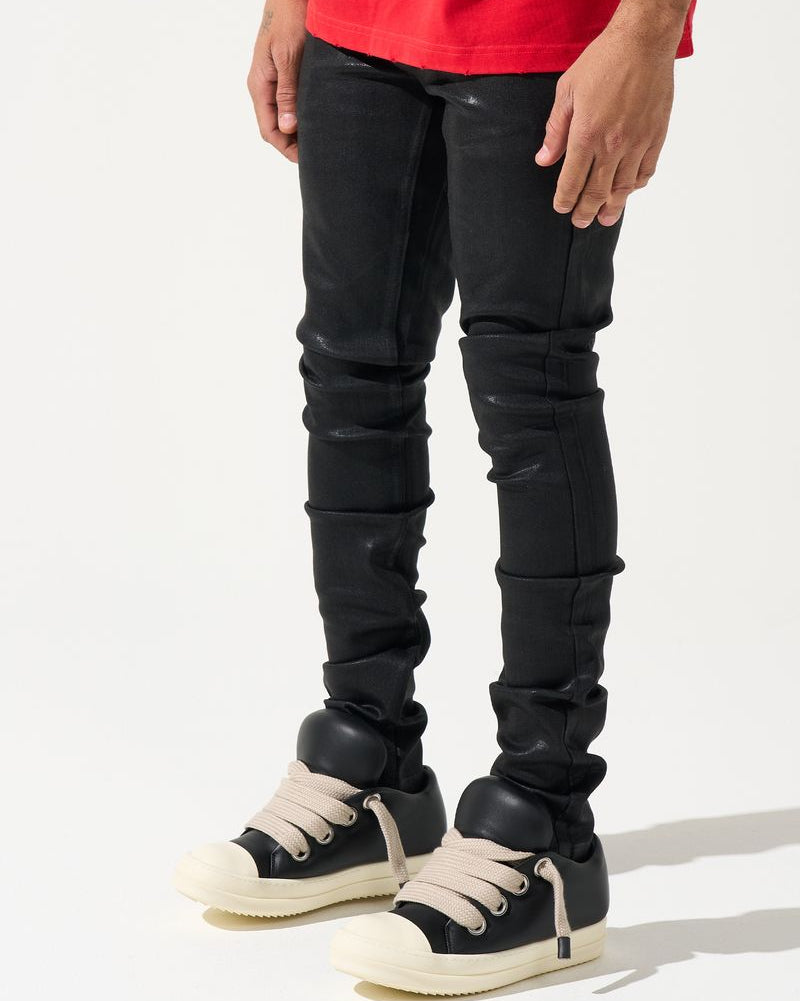 Person wearing black distressed jeans and black sneakers on a white background