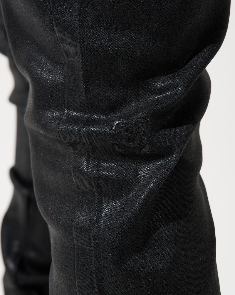 Close-up of black pants with a visible brand logo on a white background