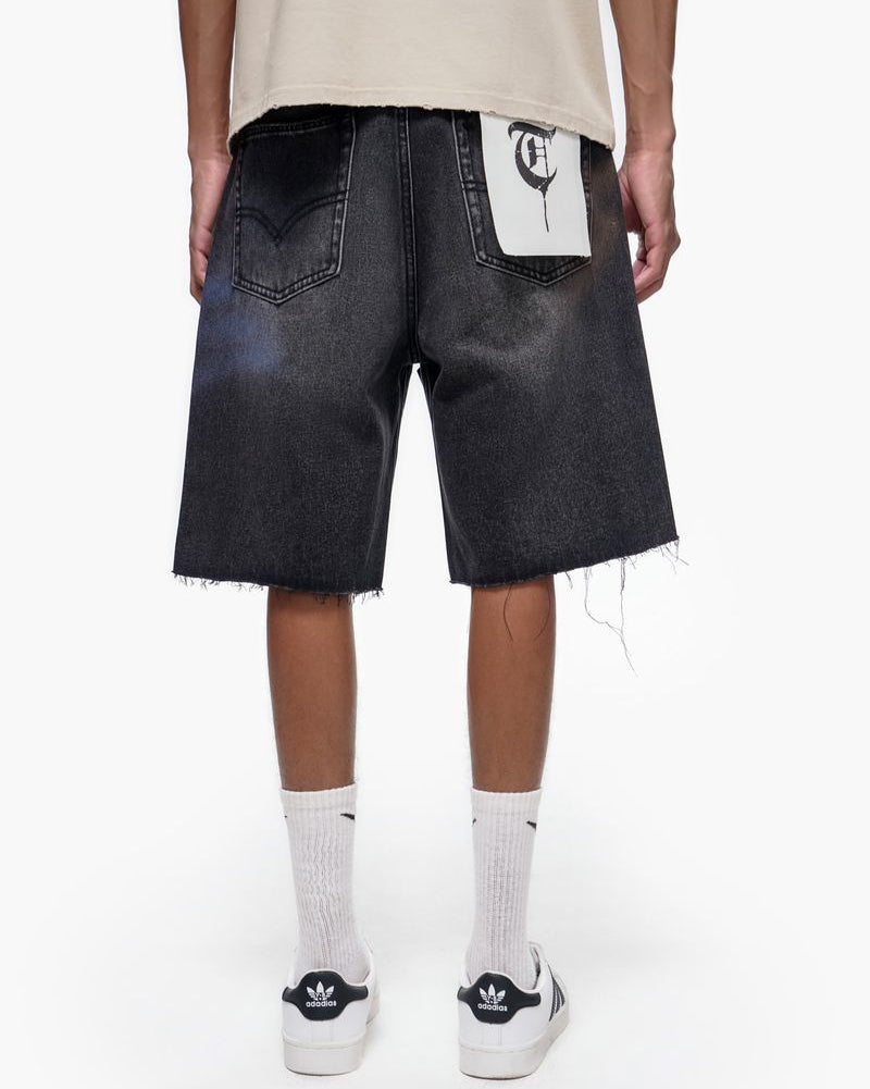 Person wearing black denim shorts with a white logo on a white background