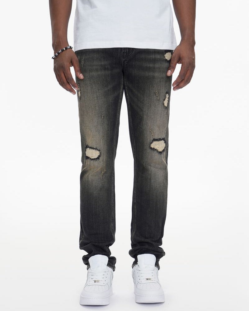 Person wearing distressed black jeans and white sneakers on a white background