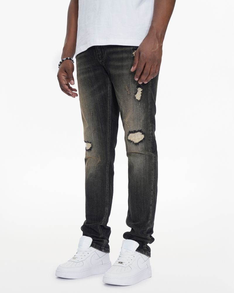 Person wearing distressed black jeans and white sneakers on a white background