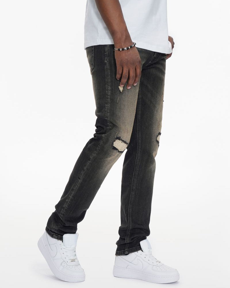 Person wearing black distressed jeans and white sneakers on a white background