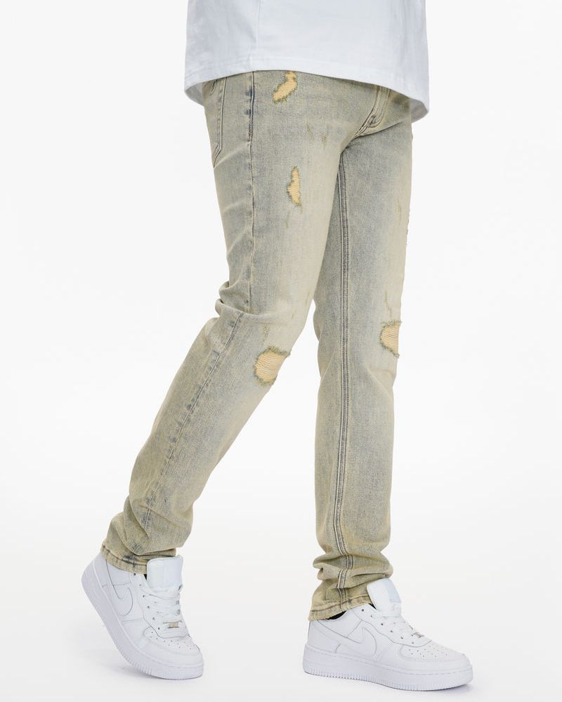 Person wearing light-colored distressed jeans and white sneakers on a white background