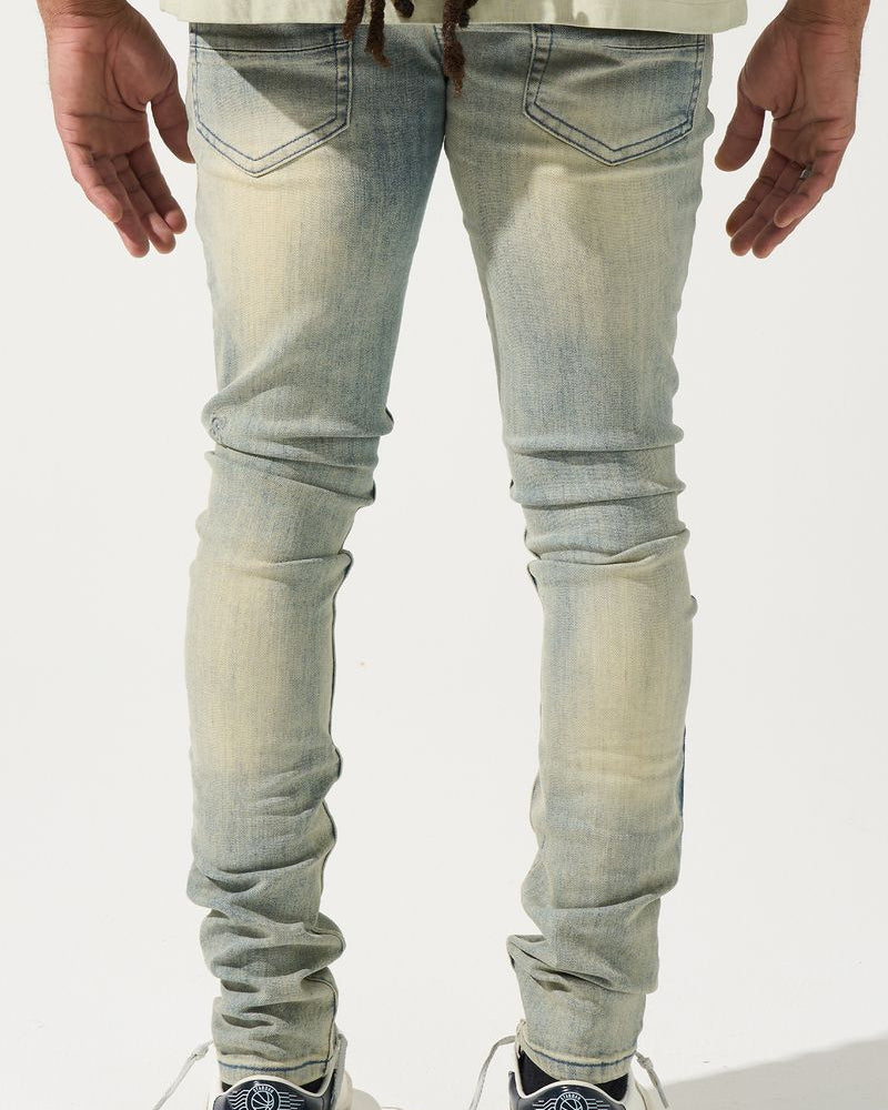 Person wearing light blue jeans and black sneakers on a white background