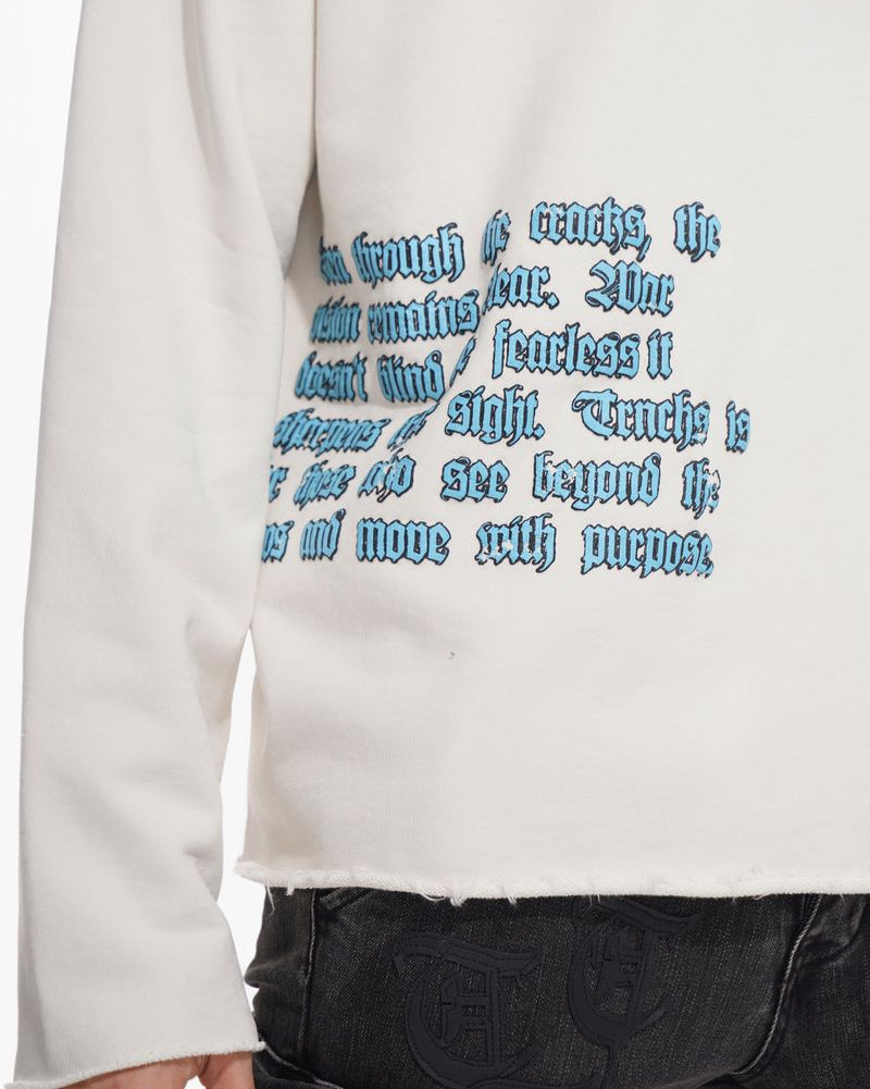 White sweatshirt with blue text design worn by a person, with a focus on the text.