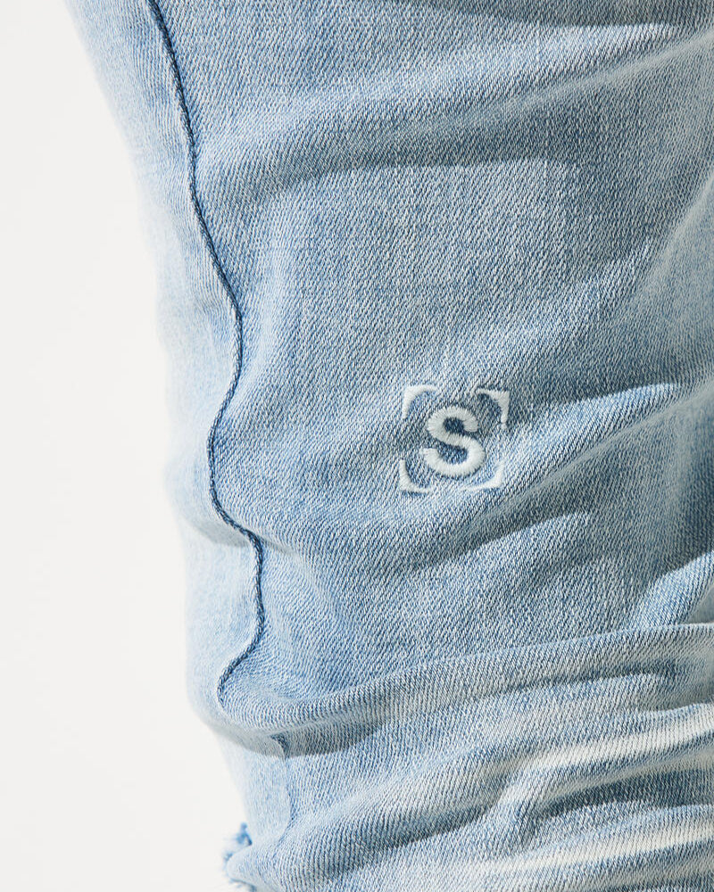 Close-up of a blue denim pocket with a brand logo on a white background