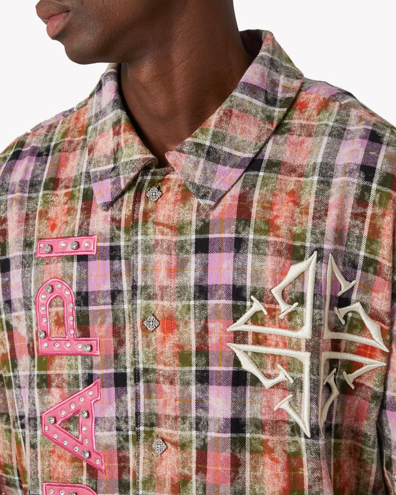 Plaid shirt with pink text and white logo worn by a person