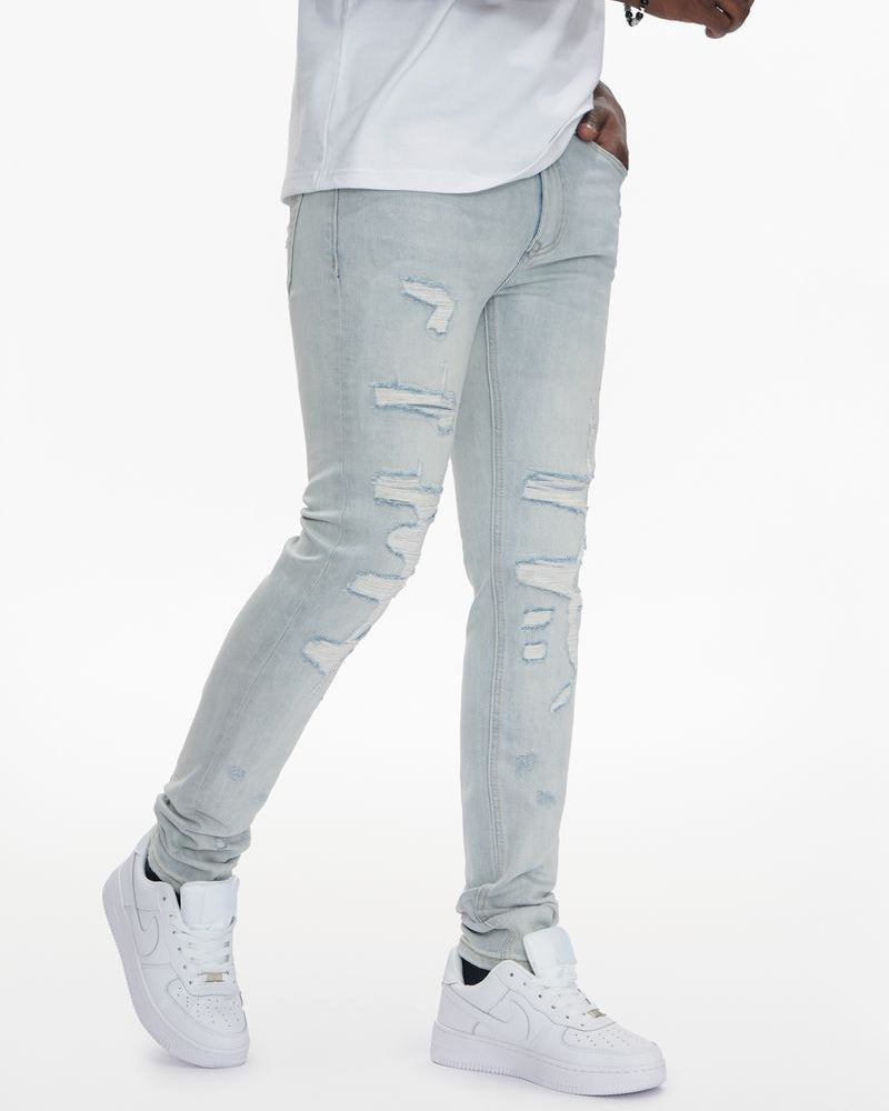 Person wearing light gray distressed jeans and white sneakers on a white background